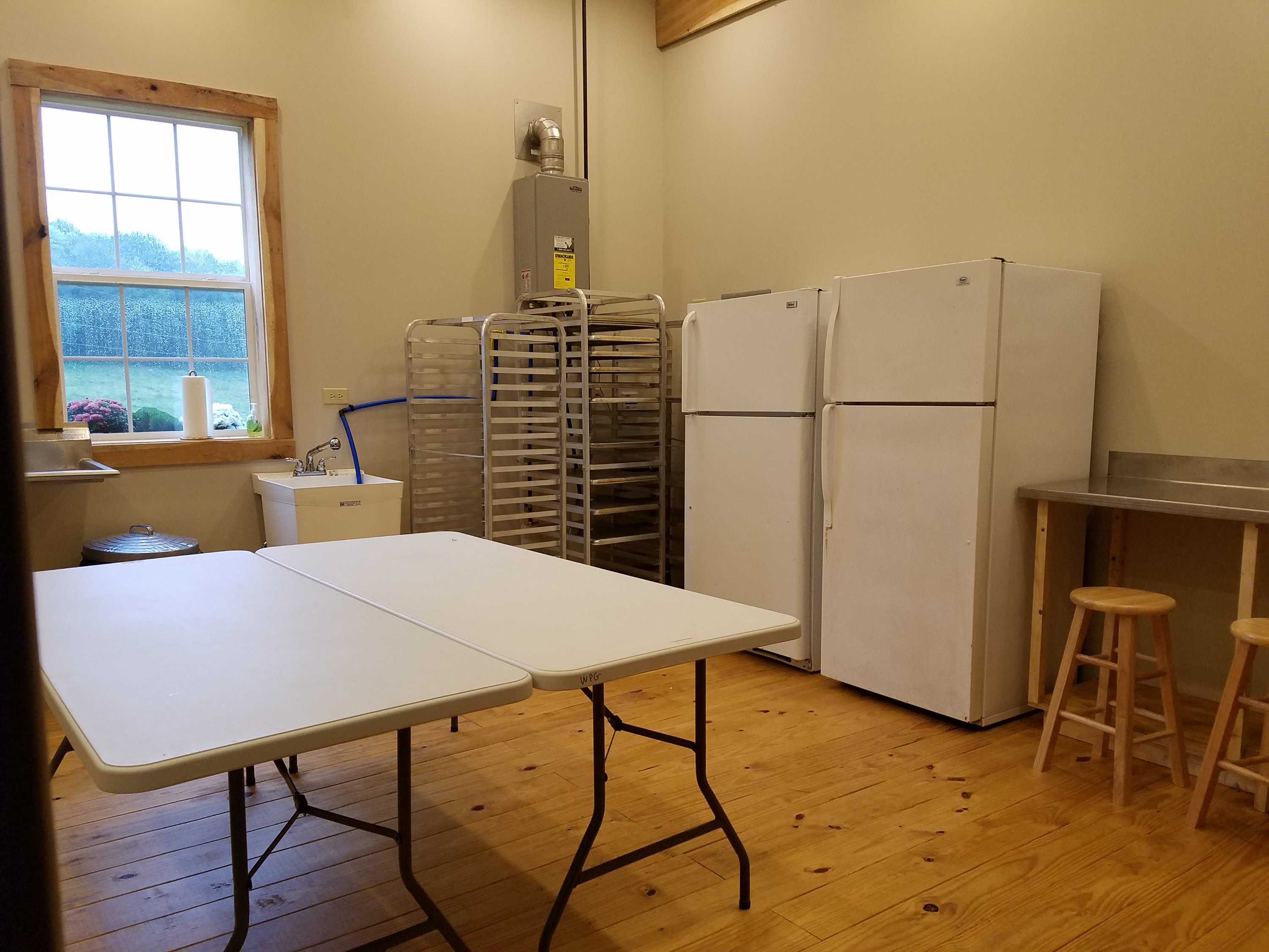 WPG kitchen right: 2 fridges, stainless steel counter top, bakers racks, tables.