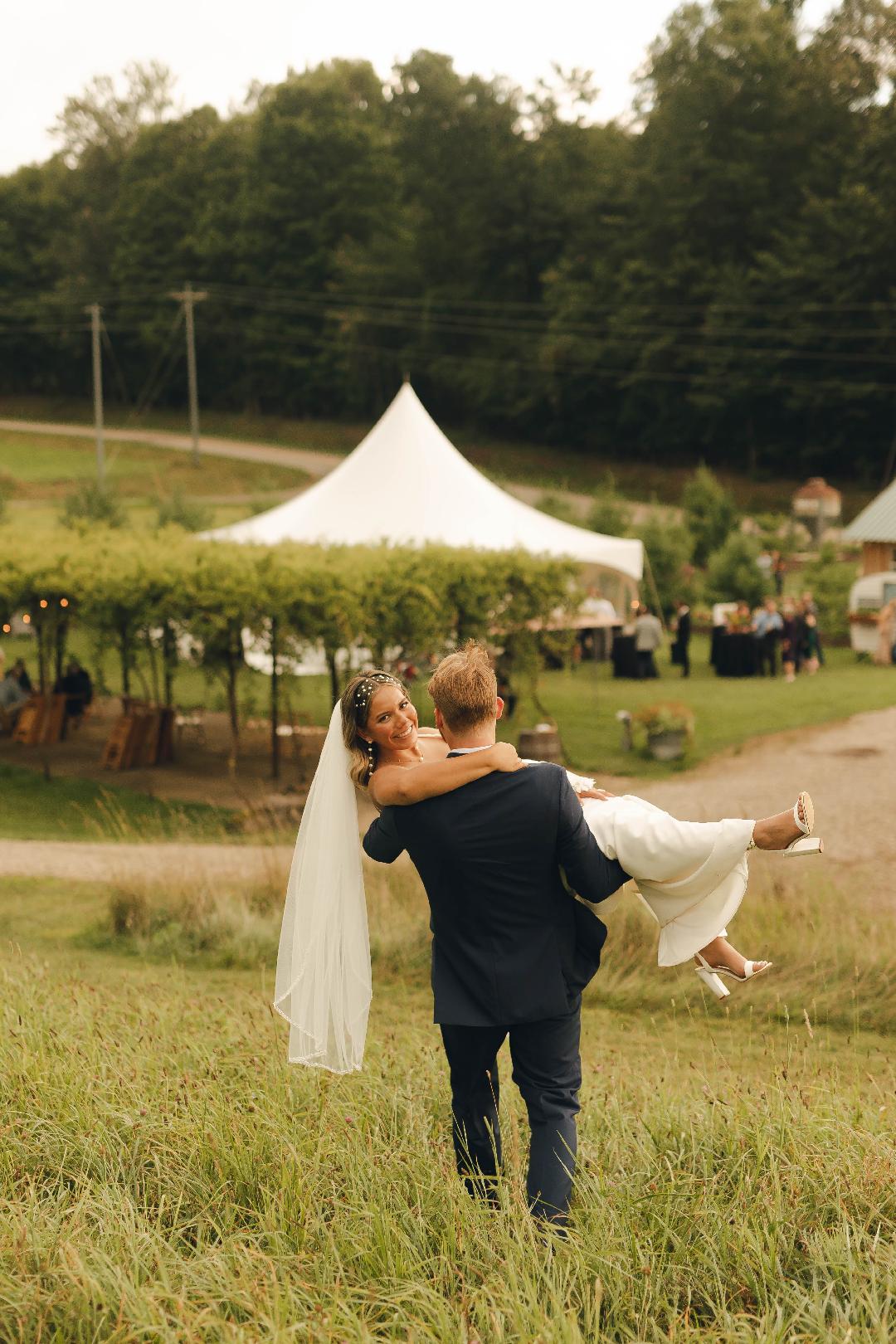 Kearston Smith Photography View of Bride and Groom coming down from pasture towards arbor at White Pine Grove